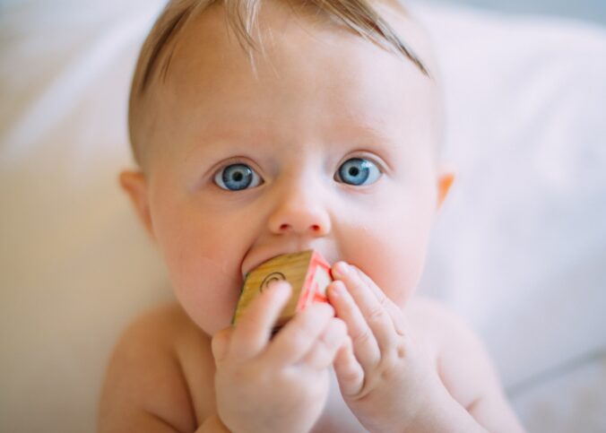 un bébé avec quelque chose dans la bouche et les mains devant après un test génétique